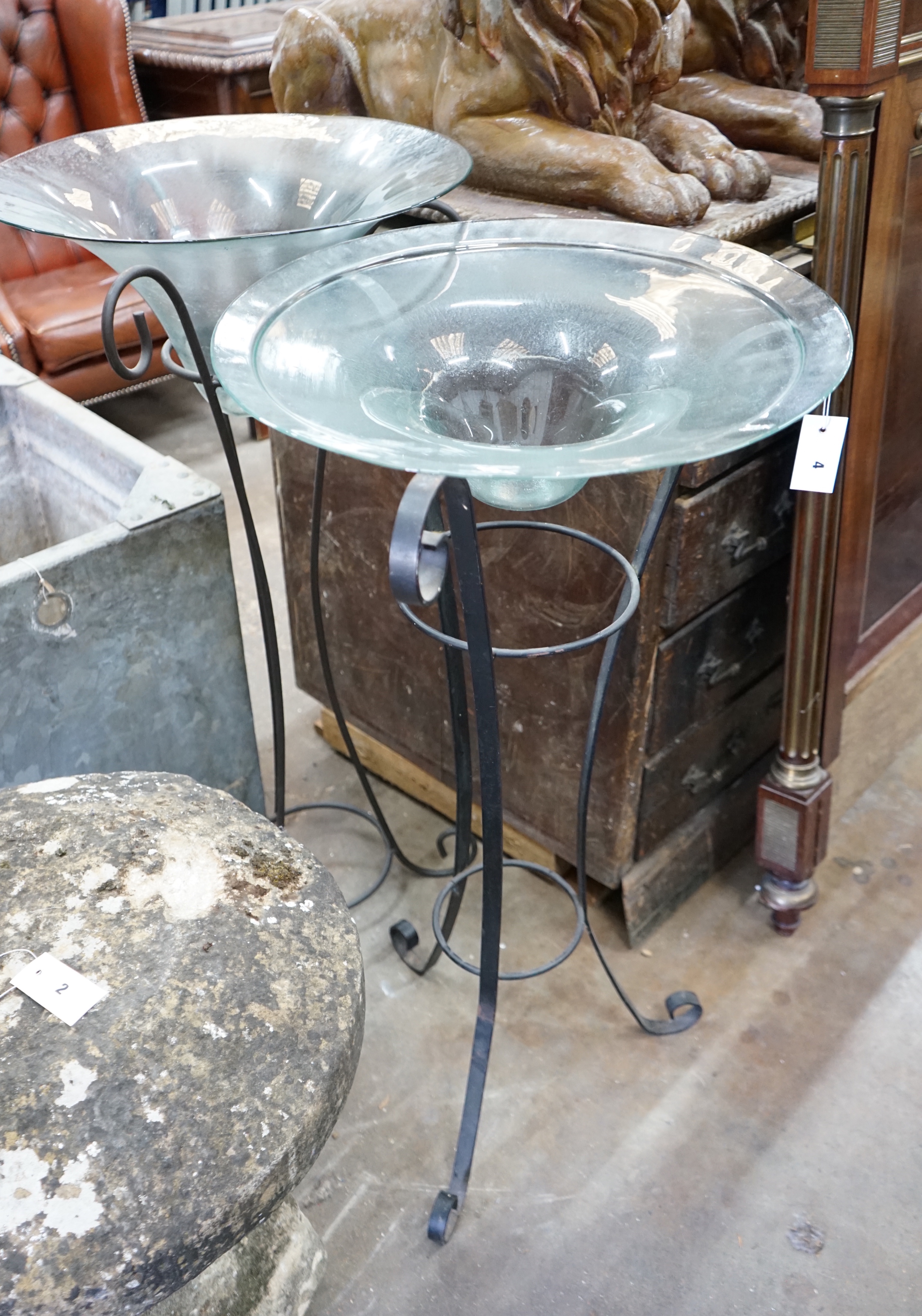 A near pair of circular glass bowls on wrought iron stands, tallest 103cm
